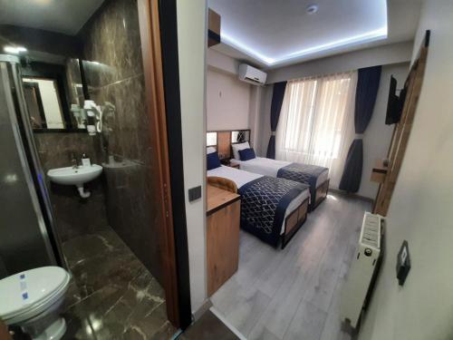 uma casa de banho com um quarto com uma cama e um lavatório em Vizyon Hotel em Istambul
