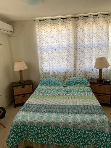 um quarto com uma cama com uma colcha verde e 2 candeeiros em Seawinds Apartments em Christ Church