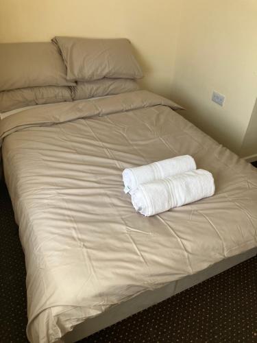 a bed with two white towels sitting on it at Entire central apartment which sleeps up to 6 in Ramsbottom