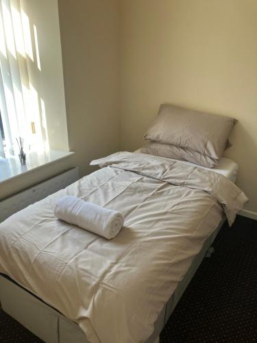 a white bed with a towel on top of it at Entire central apartment which sleeps up to 6 in Ramsbottom
