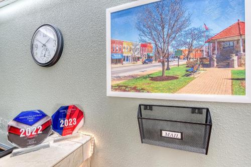 a clock on a wall with a picture and a box at American Inn & suites in Dundee
