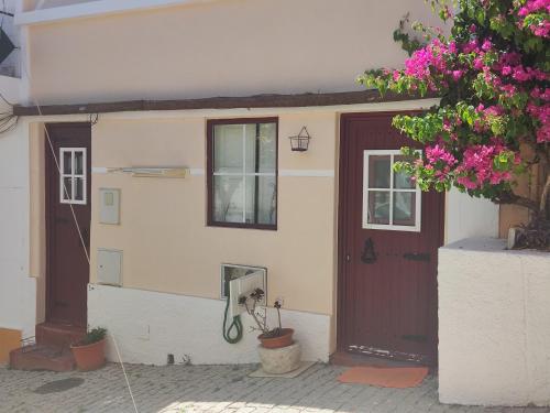 dom z brązowymi drzwiami i drzewem z różowymi kwiatami w obiekcie Poial da Bia w mieście Mértola