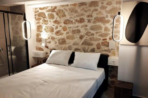 a bedroom with a white bed and a stone wall at Χώρος με επιλεκτική λιτότητα και χαμάμ in Athens