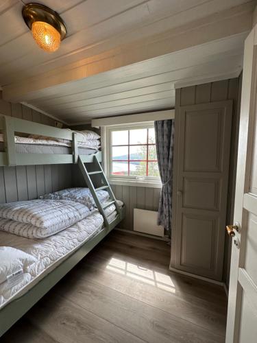 a bedroom with a bunk bed and a window at Liten og koselig hytte in Beitostøl