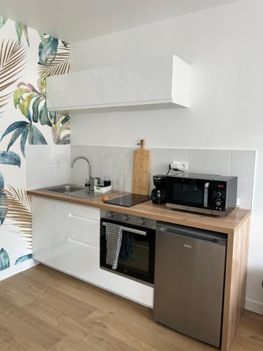 une cuisine avec un évier et un micro-ondes dans l'établissement Le Garde-Côtes, à Étel