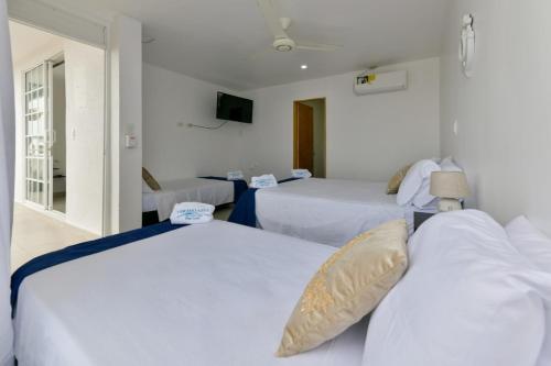 Duas camas num quarto com paredes brancas em Alojamiento Turístico Verano Azul San Andrés em San Andrés