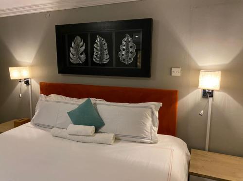 1 dormitorio con 1 cama con sábanas blancas y 2 lámparas en Ranks Guesthouse, en Molepolole