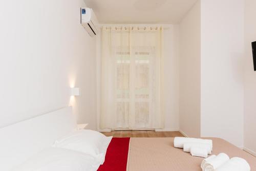 a white room with a bed with a red blanket at La Casa di Ambra in Porto Torres