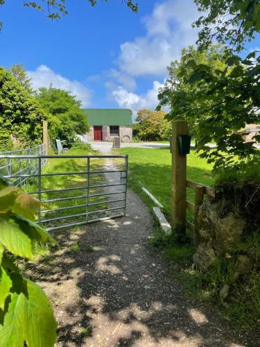 una puerta a un pasto con un granero en el fondo en Penhallow House Glamping Retreat, en Newlyn East