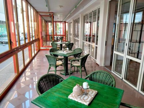 un ristorante con tavoli e sedie verdi e finestre di Hotel Stiefel a Lignano Sabbiadoro