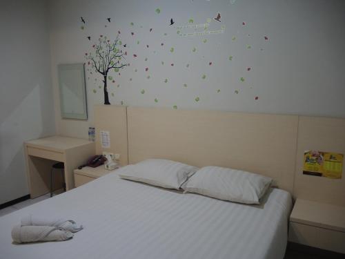 Un dormitorio con una cama blanca y un árbol en la pared en SWK 95 Hotel, en Surabaya