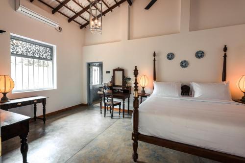 a bedroom with a bed and a desk and a table at Moi Talpe by DBI in Talpe