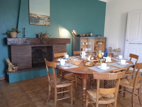 ein Esszimmer mit einem Holztisch und einem Kamin in der Unterkunft La Maison de L'Ousse in Livron