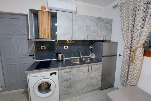 een keuken met een wastafel en een wasmachine bij villa Heljos apartaments in Vlorë
