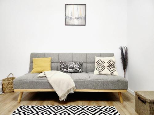 a grey couch with pillows on it in a living room at ADM Cozy Home - Entire private house&garden, close to Therme and Edenland in Tunari