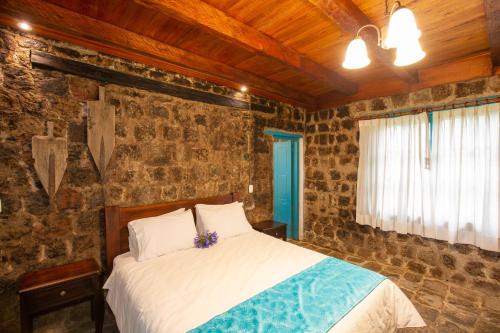 a bedroom with a bed in a room with stone walls at Niebli Historical Farm and Lodge at Pululahua Volcano in Quito