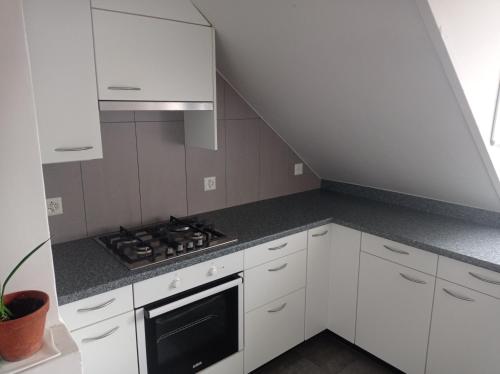 uma cozinha com armários brancos e um forno com placa de fogão em Gemütliche Dachwohnung em St. Gallen