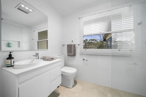a white bathroom with a toilet and a sink at Lavender Cottage in Leura