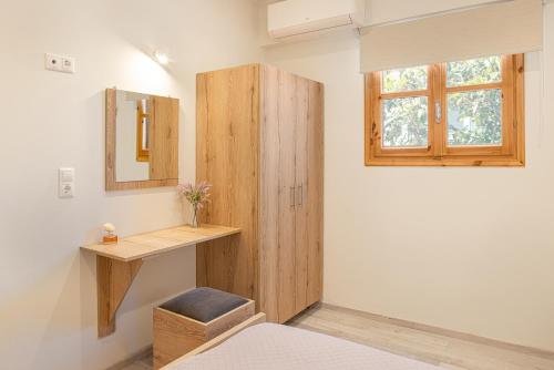 a bedroom with a wooden cabinet and a window at Fiera Luxury Apartments. in Kokkari