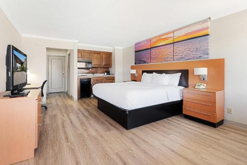 a hotel room with a bed and a flat screen tv at Days Inn & Suites by Wyndham Roseville/Detroit Area in Roseville