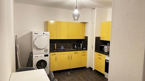 une cuisine avec des armoires jaunes et un lave-linge dans l'établissement Quartier de Plainpalais, à Genève