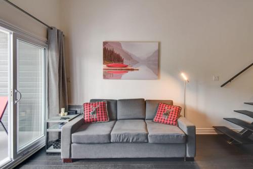 a living room with a couch and a window at Le Cozy Nest by Gestion ELITE in Mont-Tremblant