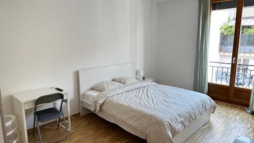 - une chambre blanche avec un lit, un bureau et une fenêtre dans l'établissement Quartier de Plainpalais, à Genève