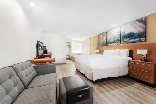 una camera d'albergo con letto e divano di Days Inn & Suites by Wyndham Roseville/Detroit Area a Roseville