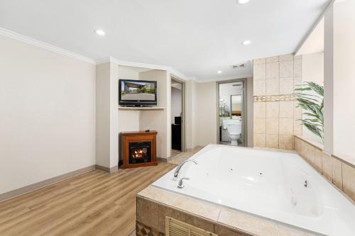 a large bathroom with a tub and a tv at Days Inn & Suites by Wyndham Roseville/Detroit Area in Roseville