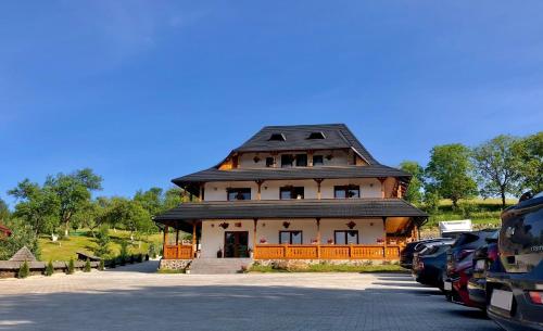 a large house with a black roof on a parking lot at Pensiunea ROCA Maramureș in Deseşti