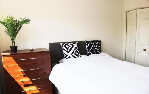um quarto com uma cama e uma cómoda com uma planta em Flat in London- Modern 2 Bedroom Apartment Harrow near Wembley em Harrow