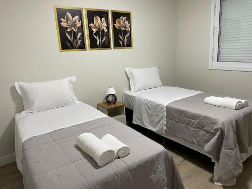 two beds in a room with white sheets and towels at Aconchego na Serra - Nova Petrópolis in Nova Petrópolis