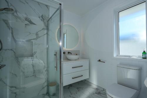 a white bathroom with a shower and a sink at Papamoa Coastal Luxury in Papamoa