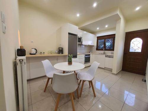 a kitchen with a table and white chairs in a room at Livas City Relaxing Apartment in Kos Town