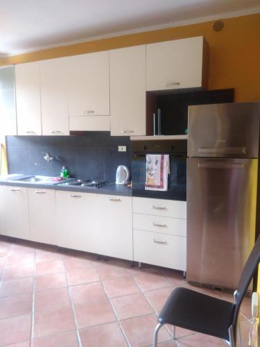 a kitchen with white cabinets and a chair in it at Appartamento Ortensia in Montale