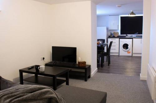 een woonkamer met een bank en een tafel met een televisie bij Spacious 1Bed Apartment in Heywood near CC in Heywood
