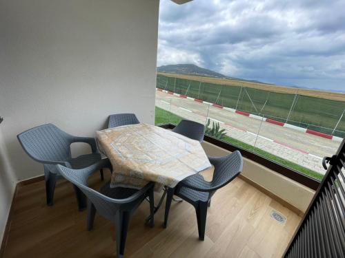 una mesa y sillas en un balcón con vistas a un campo de fútbol en Résidence Colina Smir, en M'diq