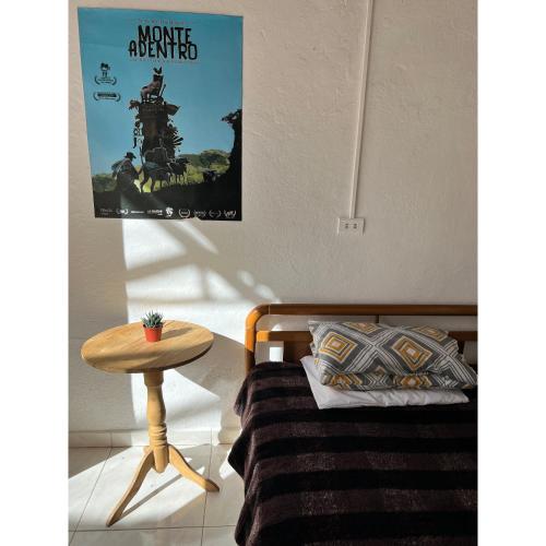 Zimmer mit einem Bett, einem Tisch und einem Poster in der Unterkunft Hostal Mamaquilla in Pasto