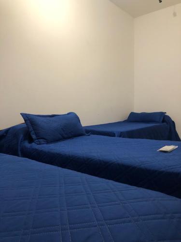 two beds with blue pillows in a room at Las chismosas in Santiago del Estero