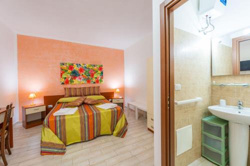 ein Schlafzimmer mit einem Bett und einem Waschbecken in einem Zimmer in der Unterkunft Villa Elisa in Torre Lapillo