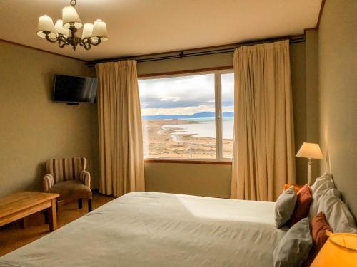 a bedroom with a bed and a large window at Hosteria La Estepa in El Calafate