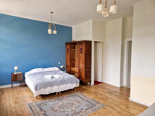 a bedroom with a bed and a blue wall at Maison du Gave in Sauveterre