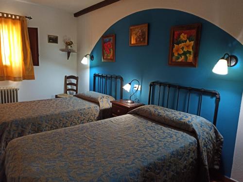 a bedroom with two beds and a blue wall at Cortijo Entresierras in Carcabuey