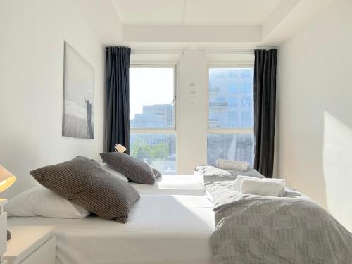 a white bedroom with two beds and a window at Modern Spacious 3 Bedroom Apartment At Ricahrd Mortensens Vej With Balcony Close To The Royal Arena And Fields in Copenhagen