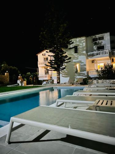 a swimming pool with lounge chairs in front of a building at Cost Mari Almyrida New by ZAGO Boutiqe hotels in Almirida