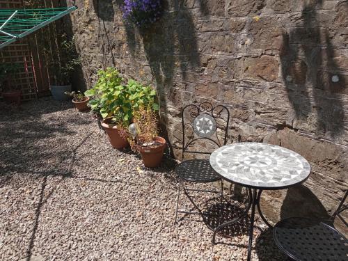 una mesa y sillas junto a una pared de piedra en Ground Floor Apt With Garden & Parking Sleeps 2, en Bodmin