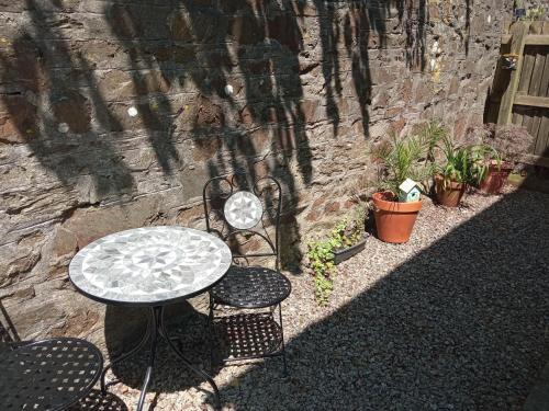 a table and chairs sitting next to a stone wall at Ground Floor Cornish Retreat Free Parking in Bodmin