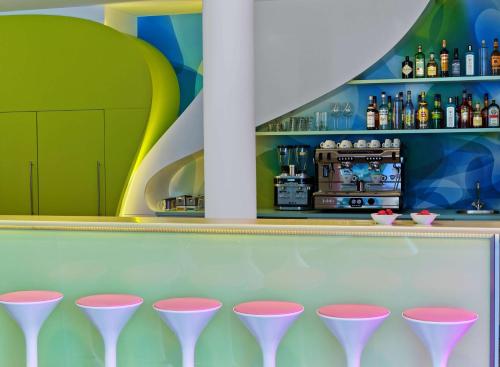 a row of pink bar stools in front of a counter at Prize by Radisson, Hamburg City in Hamburg