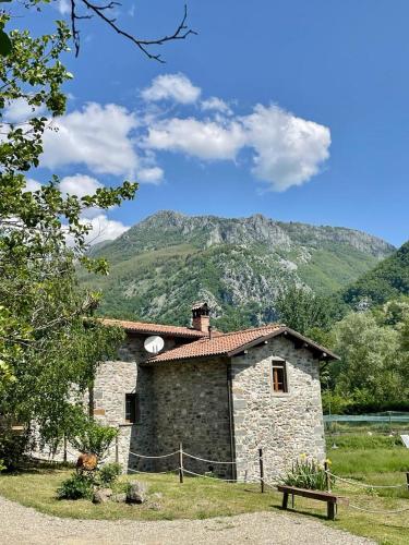 a stone building with a mountain in the background at Le Macine in Magnano