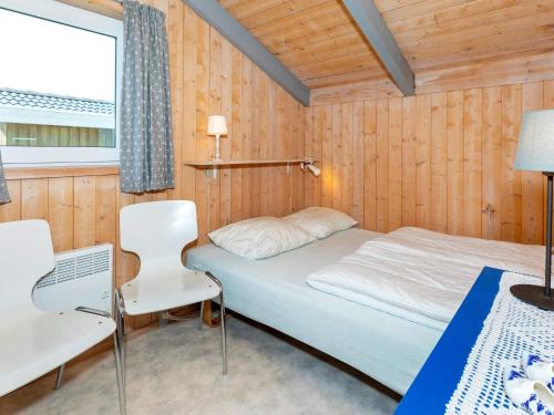 a bedroom with a bed and two chairs and a window at Secluded Haven in Thorup - By Traum Ferienwohnungen in Torup Strand